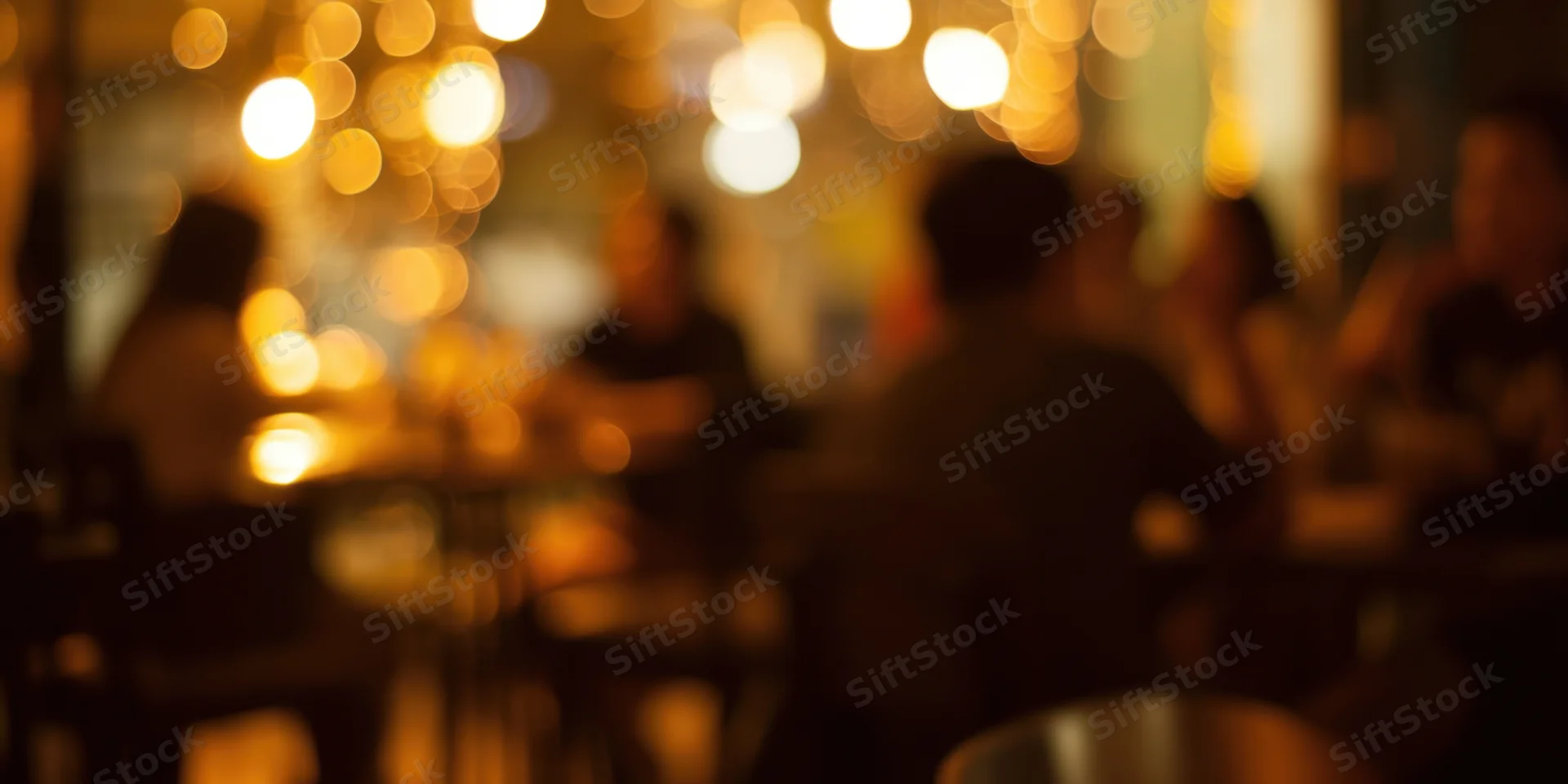 Blurred silhouettes of patrons in a warm dimly lit cafe interior