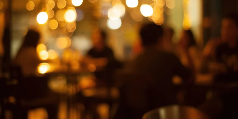 Blurred silhouettes of patrons in a warm dimly lit cafe interior