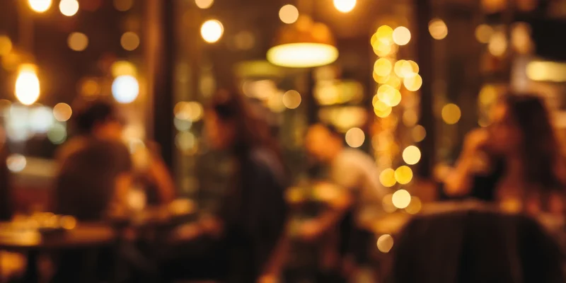 Blurred silhouettes of patrons socializing in a dimly lit cafe interior