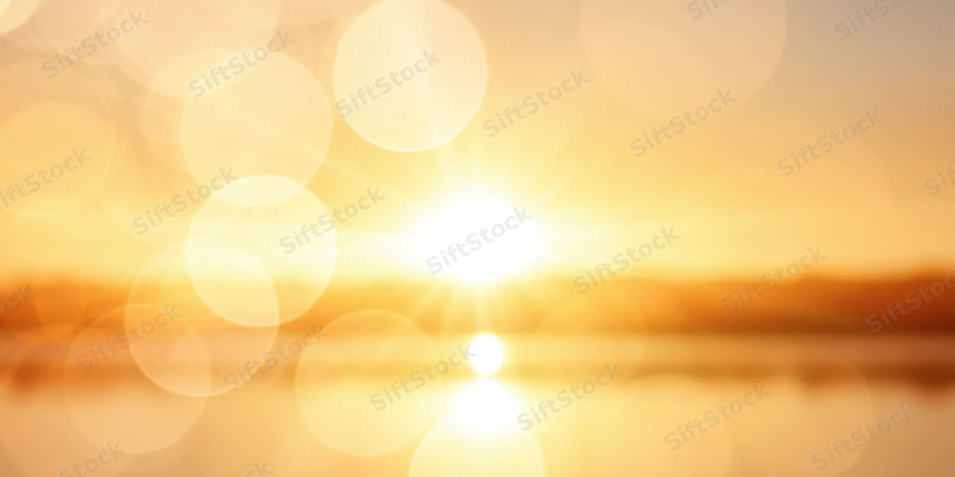 Golden sunset reflecting on calm water with bokeh light effects