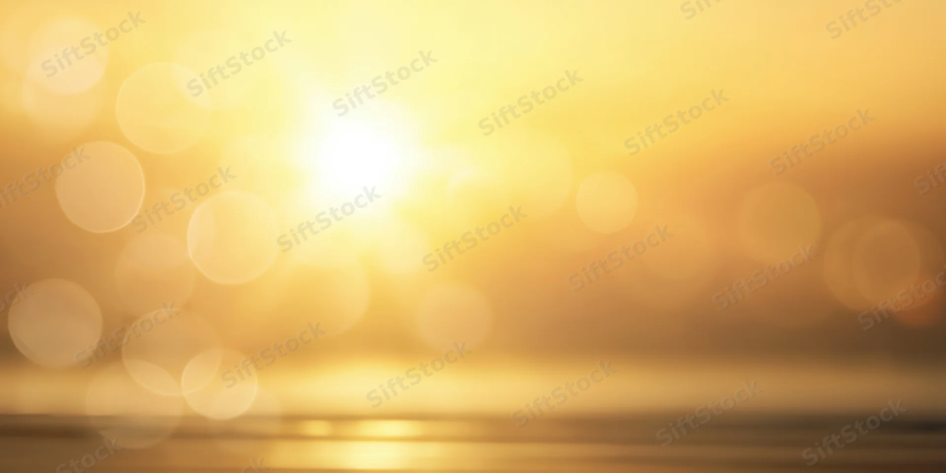 Warm golden glow with bright center and soft bokeh lights over blurred horizon and reflective surface