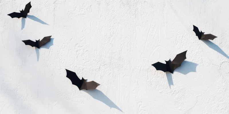 Black paper bats arranged on a white textured wall for halloween decoration