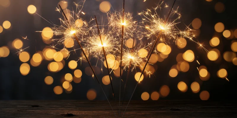 Glowing sparklers arranged in a cluster on a dark wooden surface with bokeh lights in the background