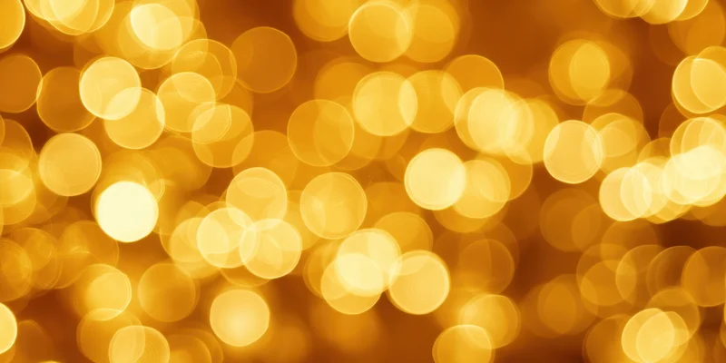 Golden bokeh lights arranged in a warm abstract background with soft glow and circular blur