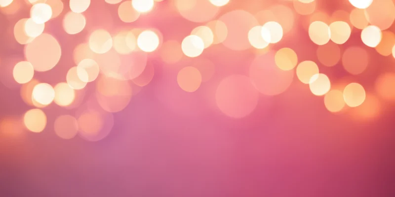 Soft pink bokeh background with warm glowing orbs of light arranged across the top, leaving copyspace below