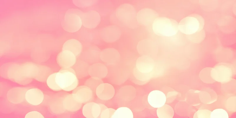Soft pink bokeh background with warm glowing orbs of light scattered across the frame