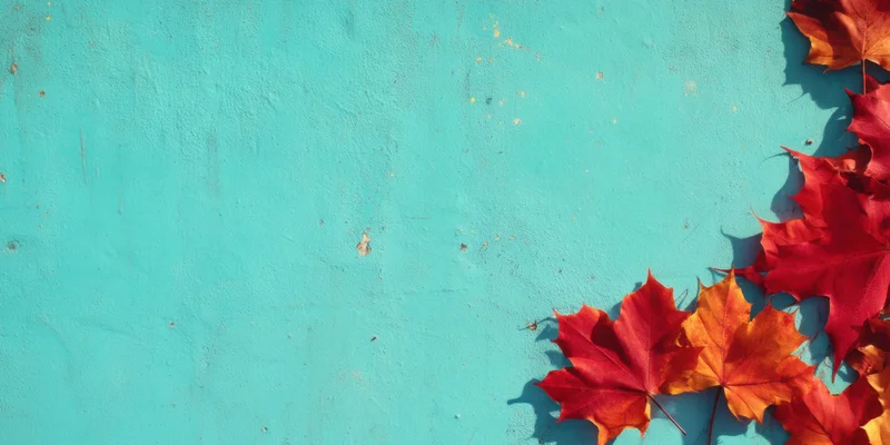 Red and orange maple leaves arranged in corner on chipped turquoise wall