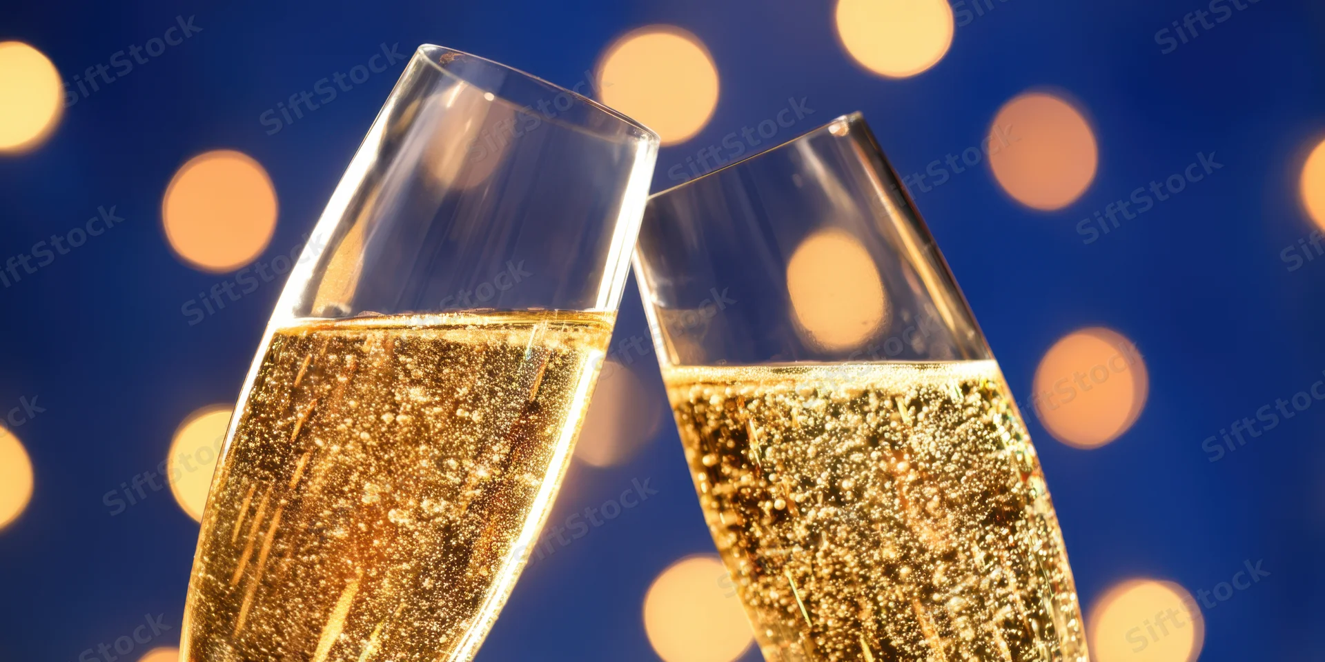 Two champagne flutes clinking with golden bubbles against a blue bokeh light background