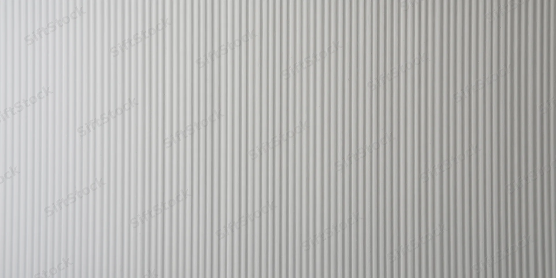 Close-up of a pale grey ribbed surface with vertical grooves forming a repeating linear pattern