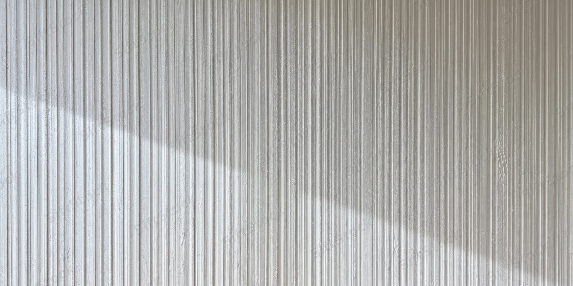Pale grey ribbed surface with vertical grooves and soft shadow across the wall