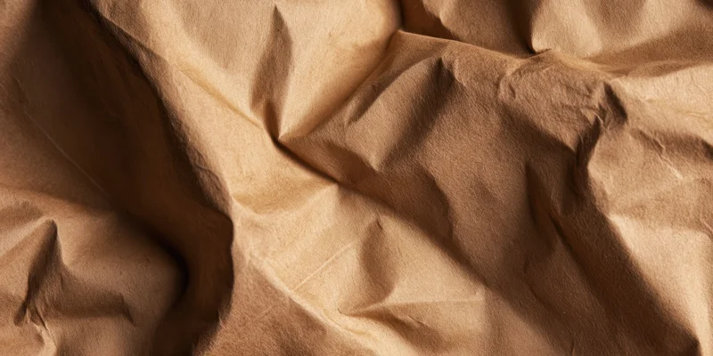 Crumpled brown kraft paper with deep creases and folds filling the frame