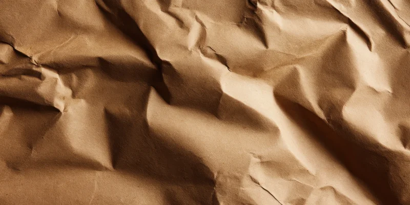 Crumpled brown kraft paper with deep creases filling the frame
