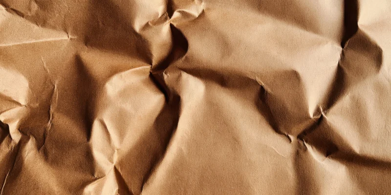 Crumpled brown kraft paper with deep creases filling the frame