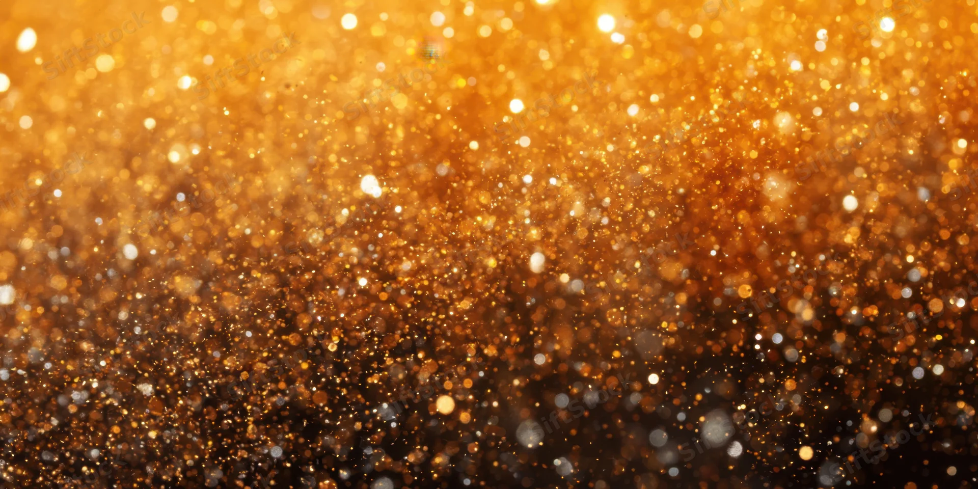 Shimmering gold glitter suspended in air forming a sparkling abstract background
