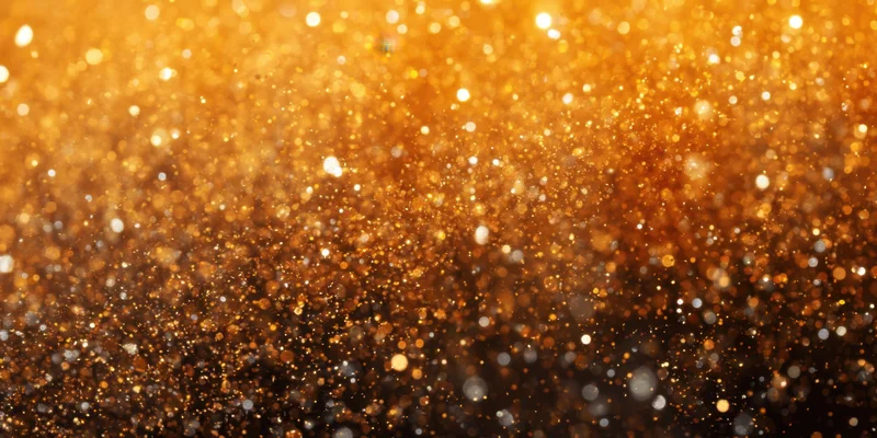 Shimmering gold glitter suspended in air forming a sparkling abstract background