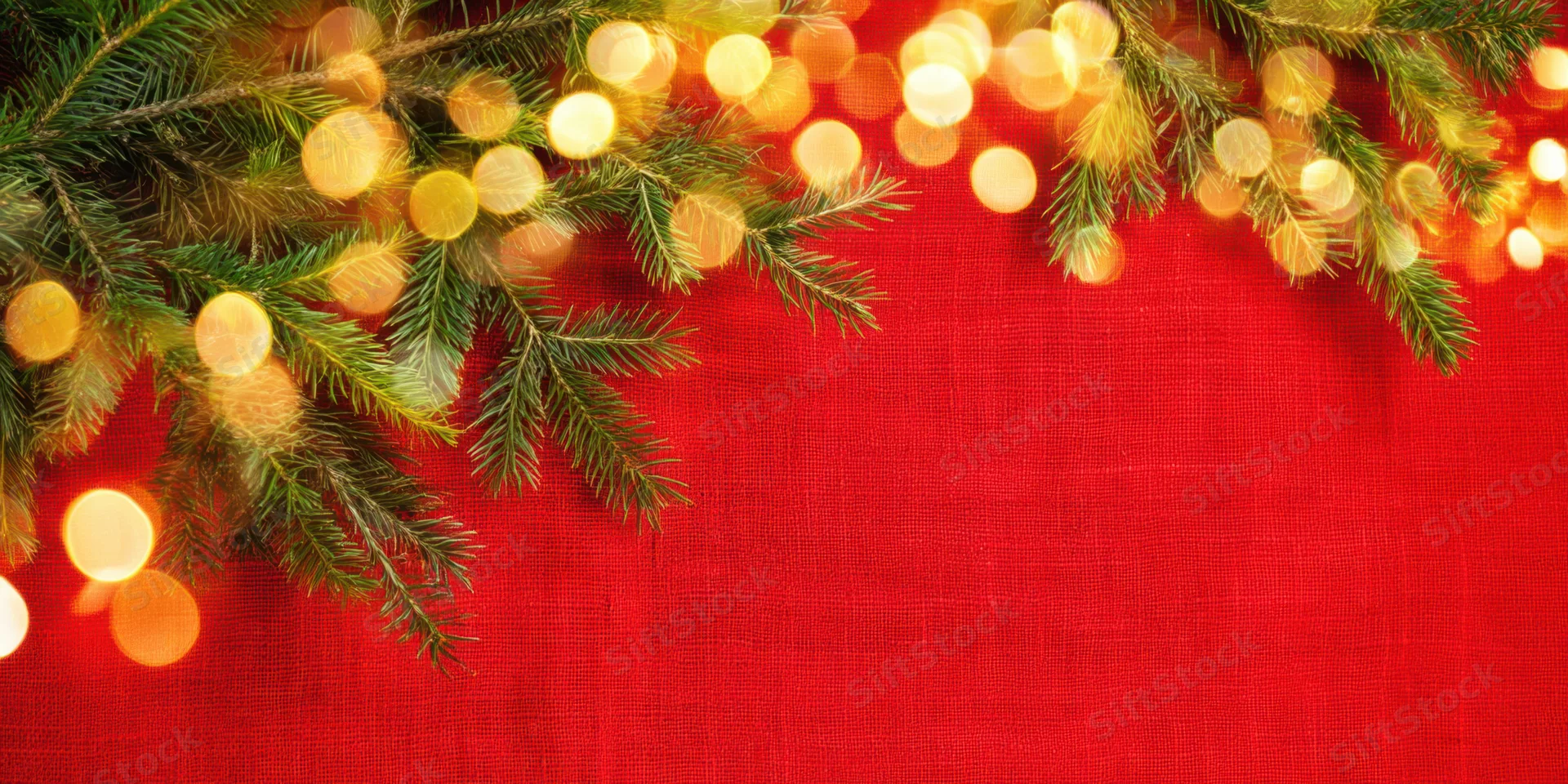 Pine branches with warm bokeh lights arranged across red textured linen background