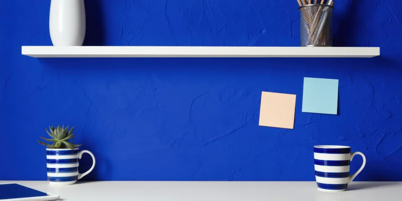 Minimalist desk setup with striped mugs and succulent plant against cobalt blue textured wall
