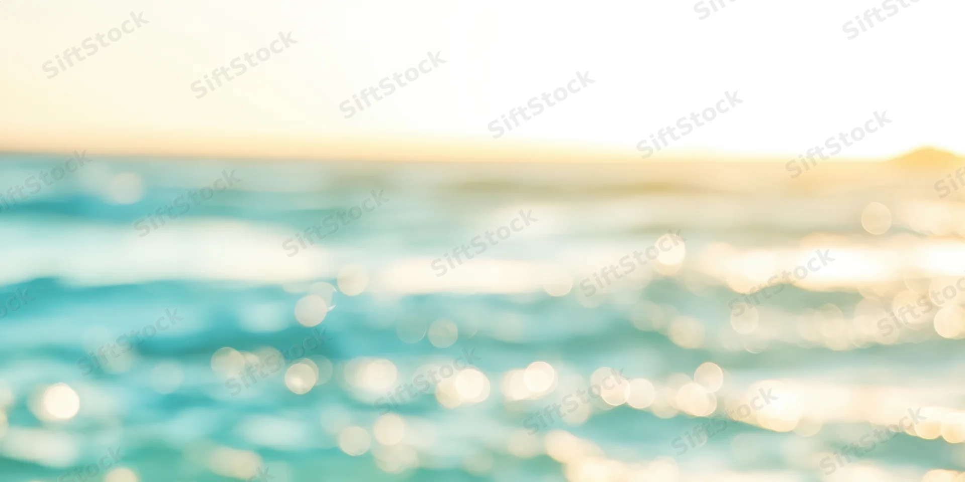 Sunlit ocean surface with golden sunrise glow and bokeh reflections at dawn