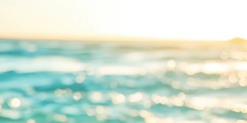 Sunlit ocean surface with golden sunrise glow and bokeh reflections at dawn