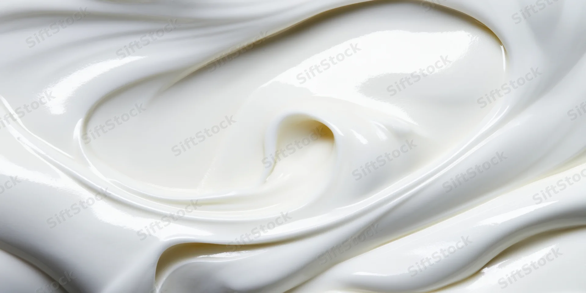 Close-up of smooth white cream with flowing swirls and glossy texture