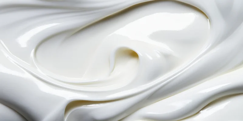 Close-up of smooth white cream with flowing swirls and glossy texture