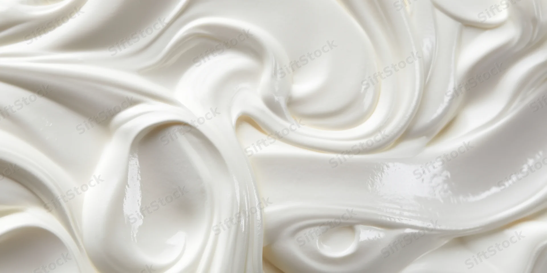 Close-up of smooth white cream with flowing swirls and glossy texture
