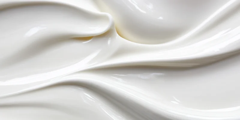 Close-up of silky white cream with smooth flowing swirls and glossy texture