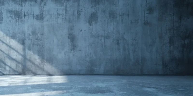 Weathered concrete wall and empty floor in cool blue light with window shadow