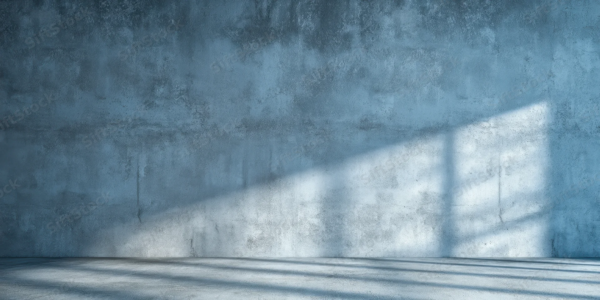 Weathered concrete wall and empty floor with sunlight casting window shadows in an industrial interior