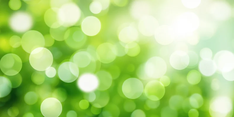 Bright green bokeh background with soft focus and sunlit glow