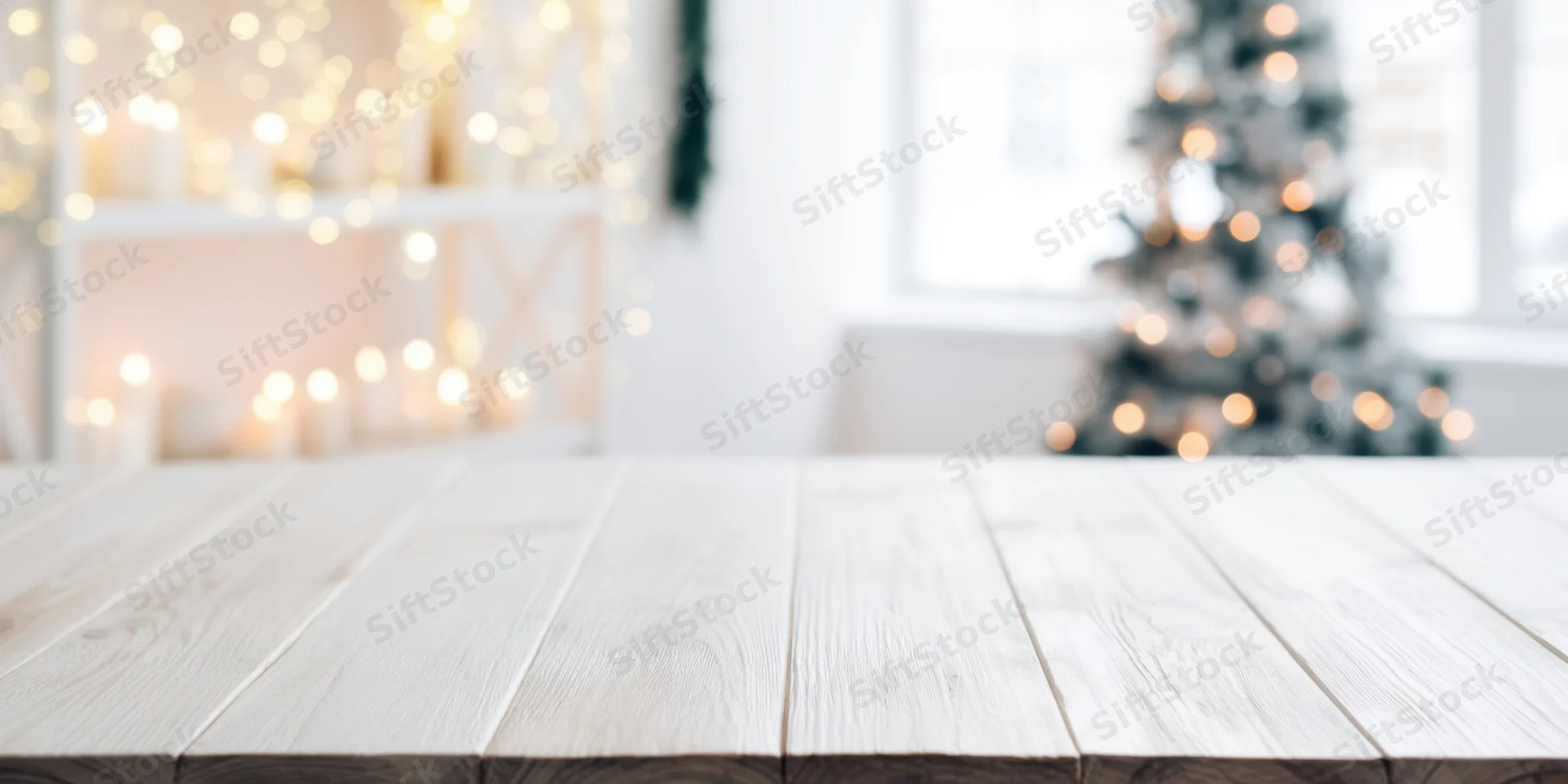 Light wooden table in front of blurred christmas decor with bokeh lights and copyspace