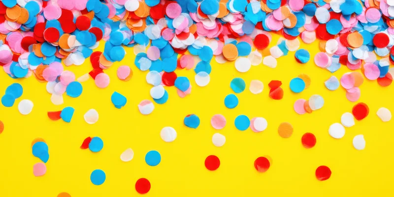 Colorful confetti scattered across a bright yellow background with copyspace