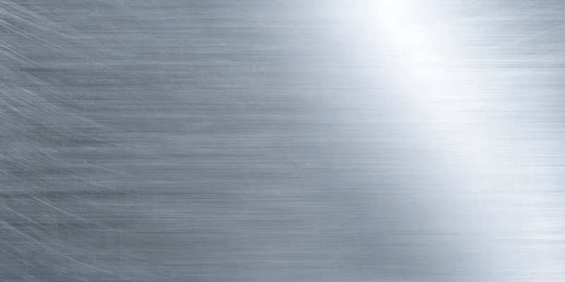 Brushed metal surface with subtle grain and soft reflect, showing a smooth reflective texture with light gradient across the frame