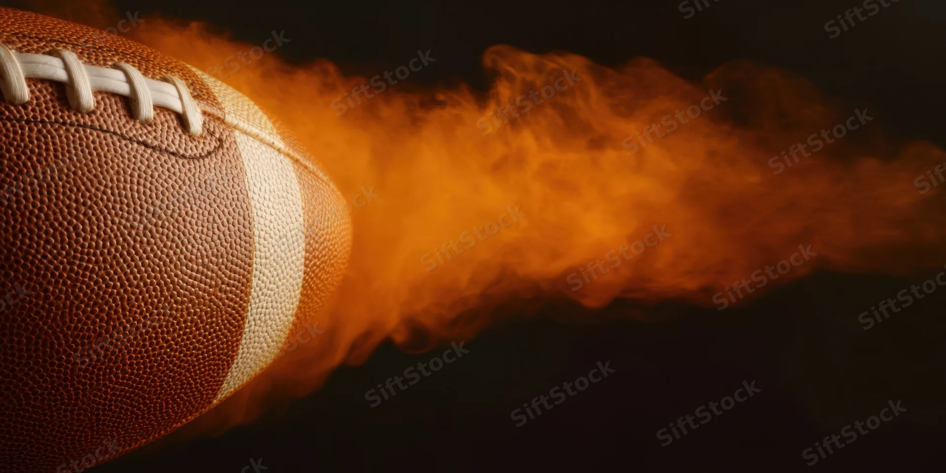 Close-up of an american football with flames trailing behind it against a dark background