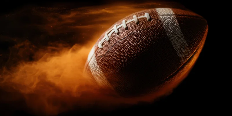 American football in motion with fiery smoke trail against dark background