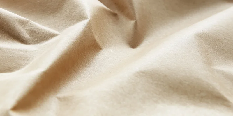 Close-up of beige kraft paper with deep creases and soft lighting