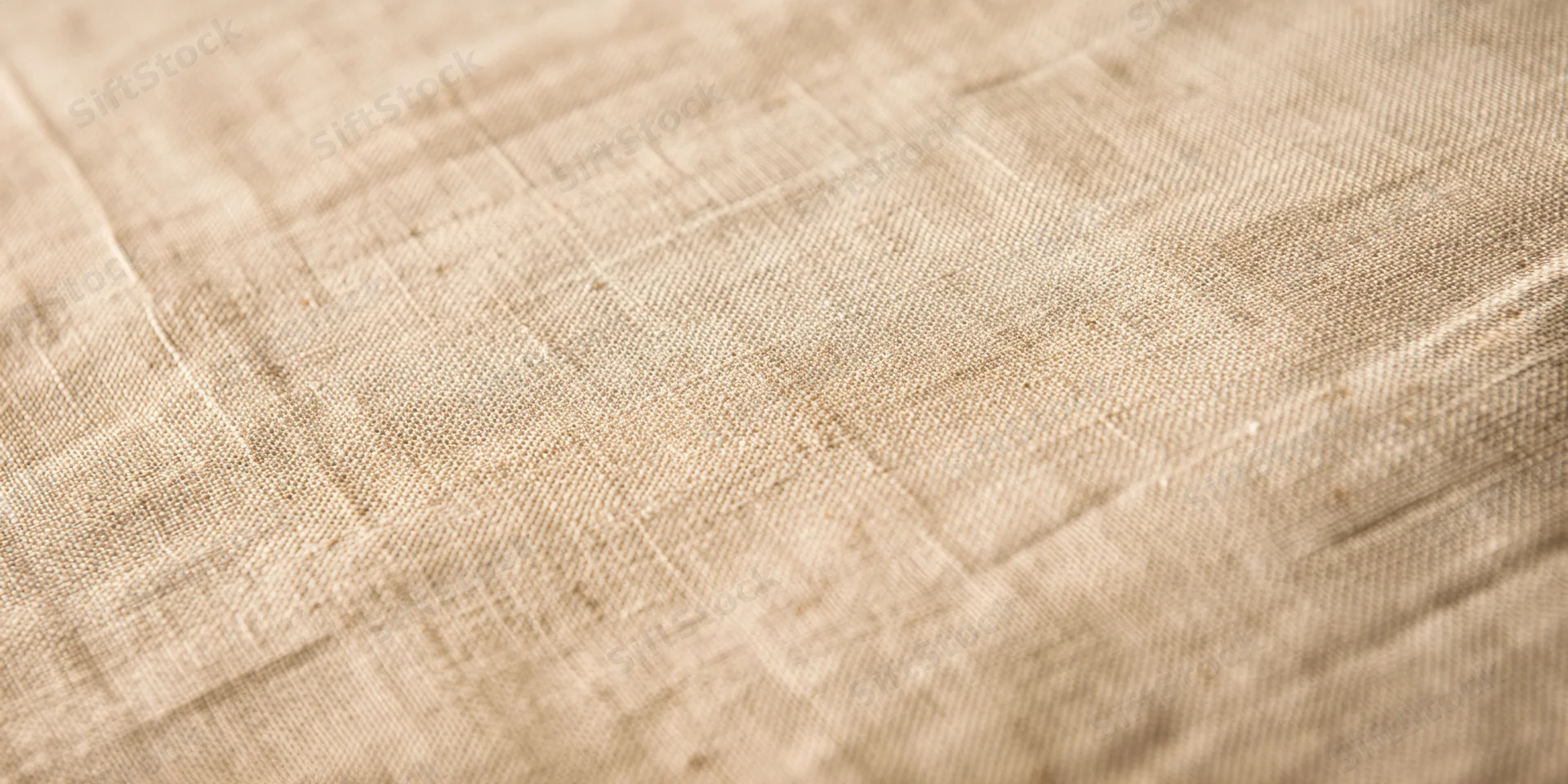 Close-up of beige linen fabric with fine woven texture filling the frame