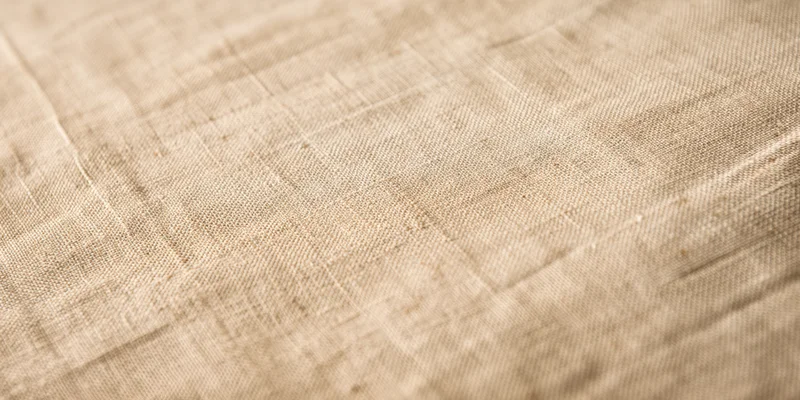 Close-up of beige linen fabric with fine woven texture filling the frame