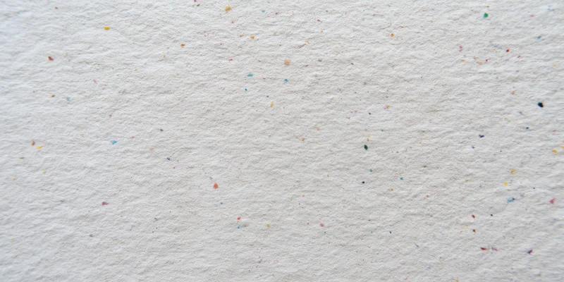 Close-up of textured off-white paper surface with scattered multicolored speckles