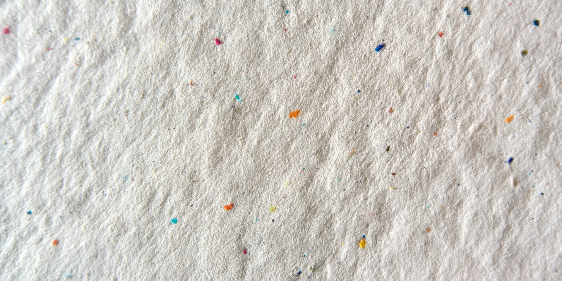 Close-up of textured off-white paper surface with scattered multicolored specks