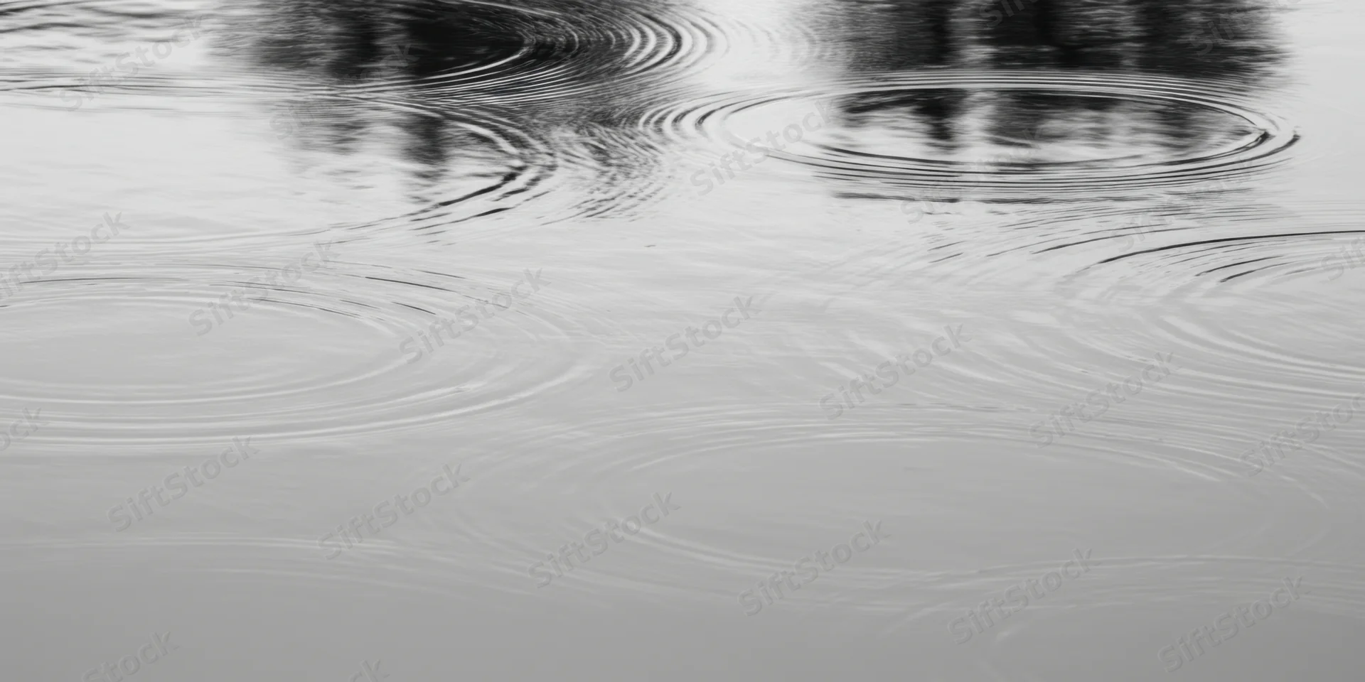 Calm water surface with concentric ripples spreading from raindrops