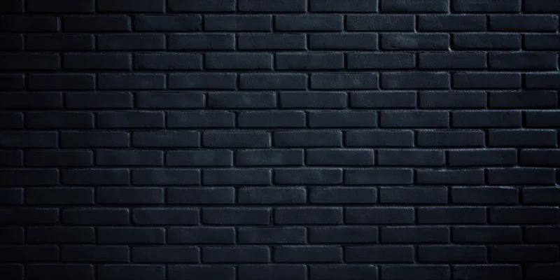 Dark brick wall with even low lighting and subtle texture filling the frame