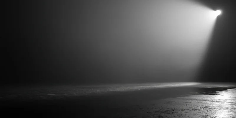 A single beam of light cuts through thick fog on a dark stage