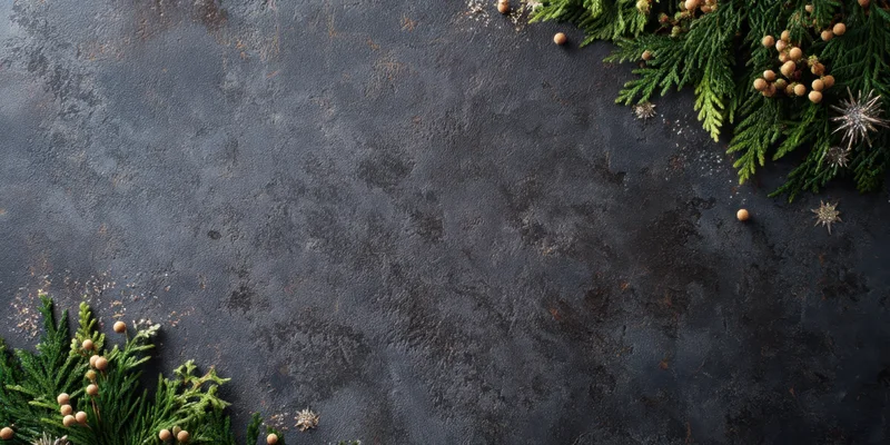 Evergreen branches and festive ornaments arranged in corners on dark textured slate background with copyspace
