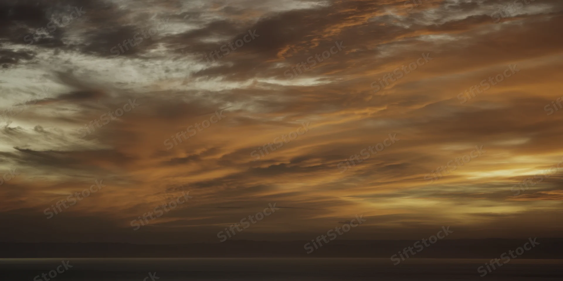 Moody sunset sky with textured orange-brown clouds over calm ocean and distant horizon
