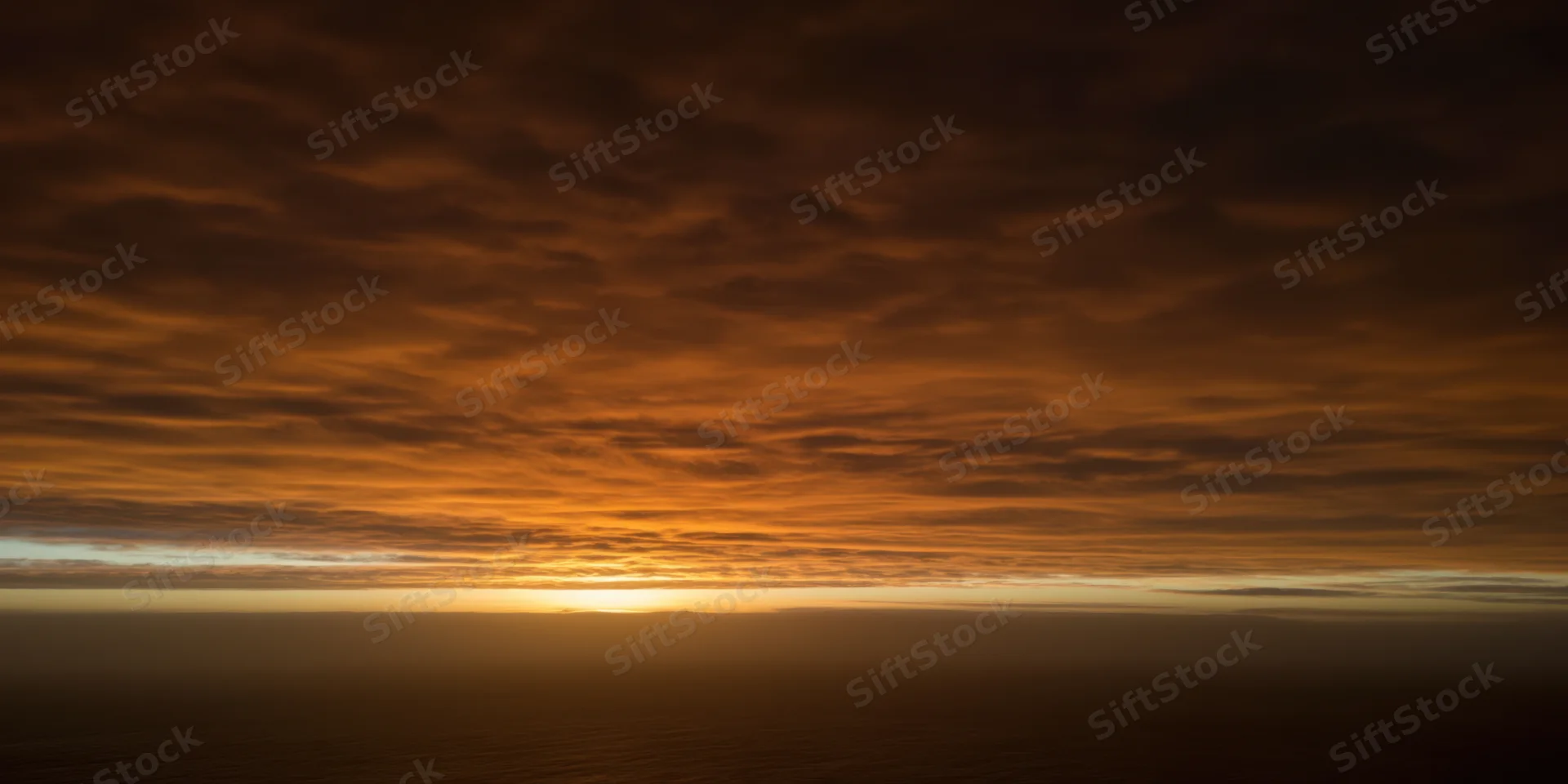 Textured orange-brown clouds over horizon during sunset sky view