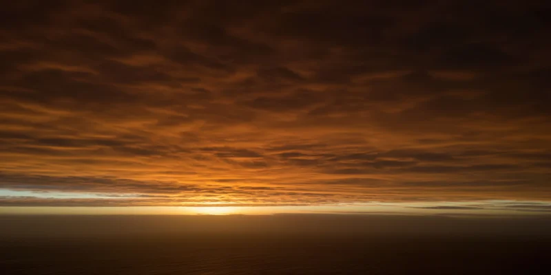 Textured orange-brown clouds over horizon during sunset sky view