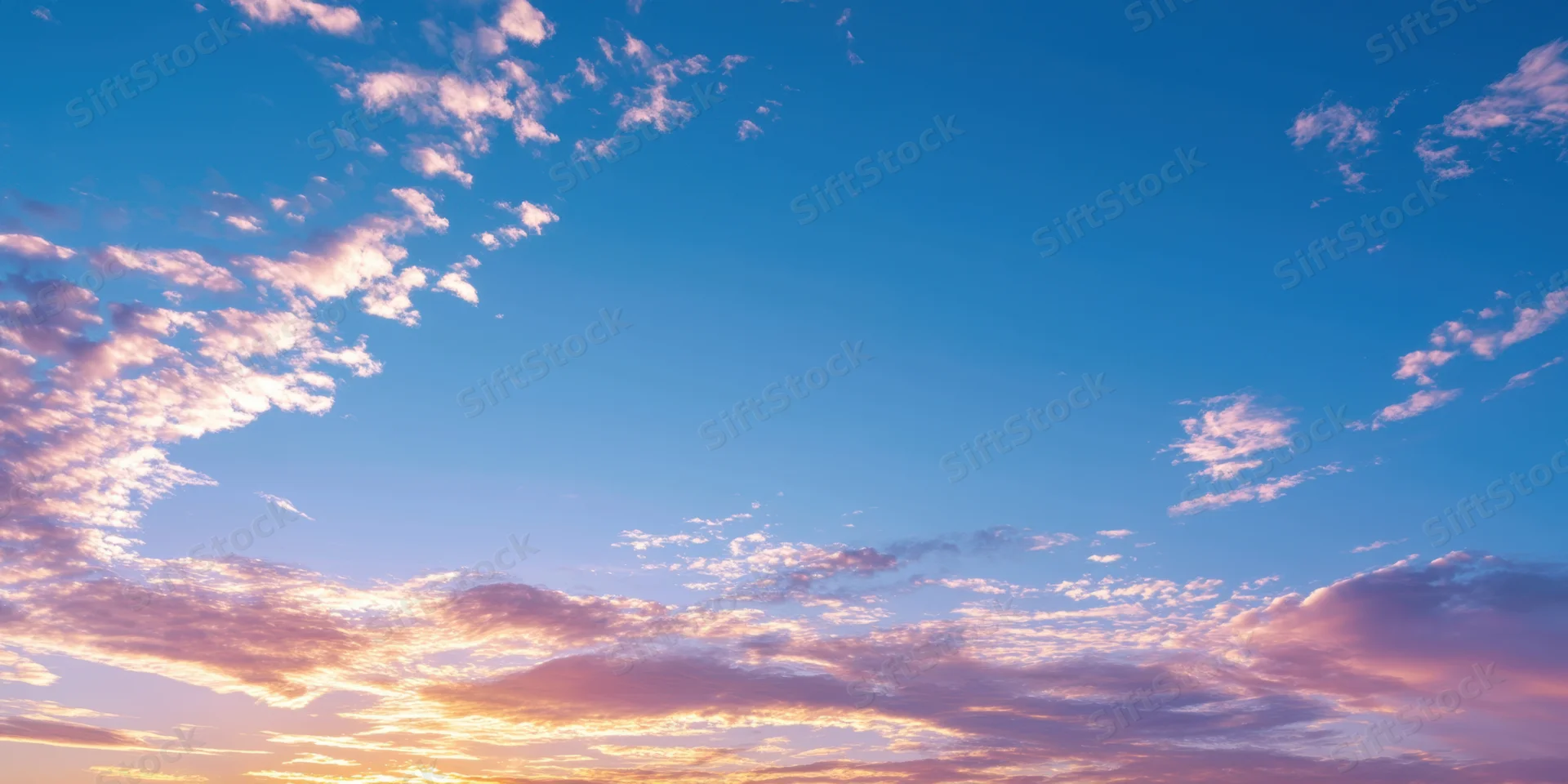 Sunrise sky with soft pink and orange clouds against a blue gradient horizon