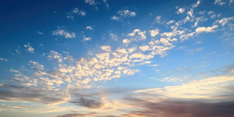 Sunrise sky with scattered clouds transitioning from cobalt blue to warm golden hues at horizon