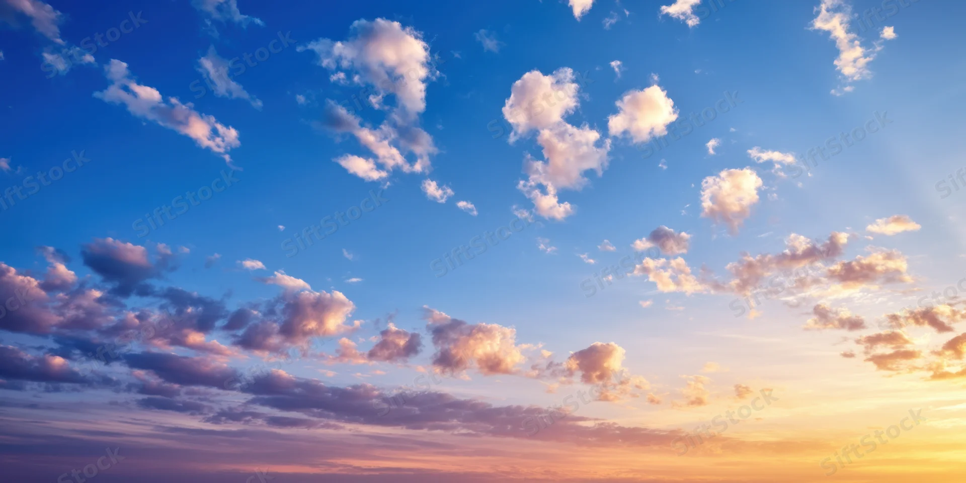 Sky with scattered clouds transitioning from cobalt blue to warm orange at sunrise